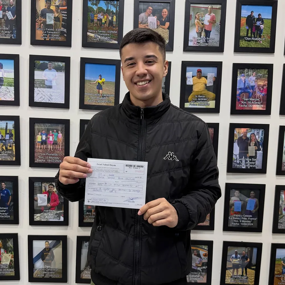 Un cliente con su contrato firmado frente a la pared de la oficina